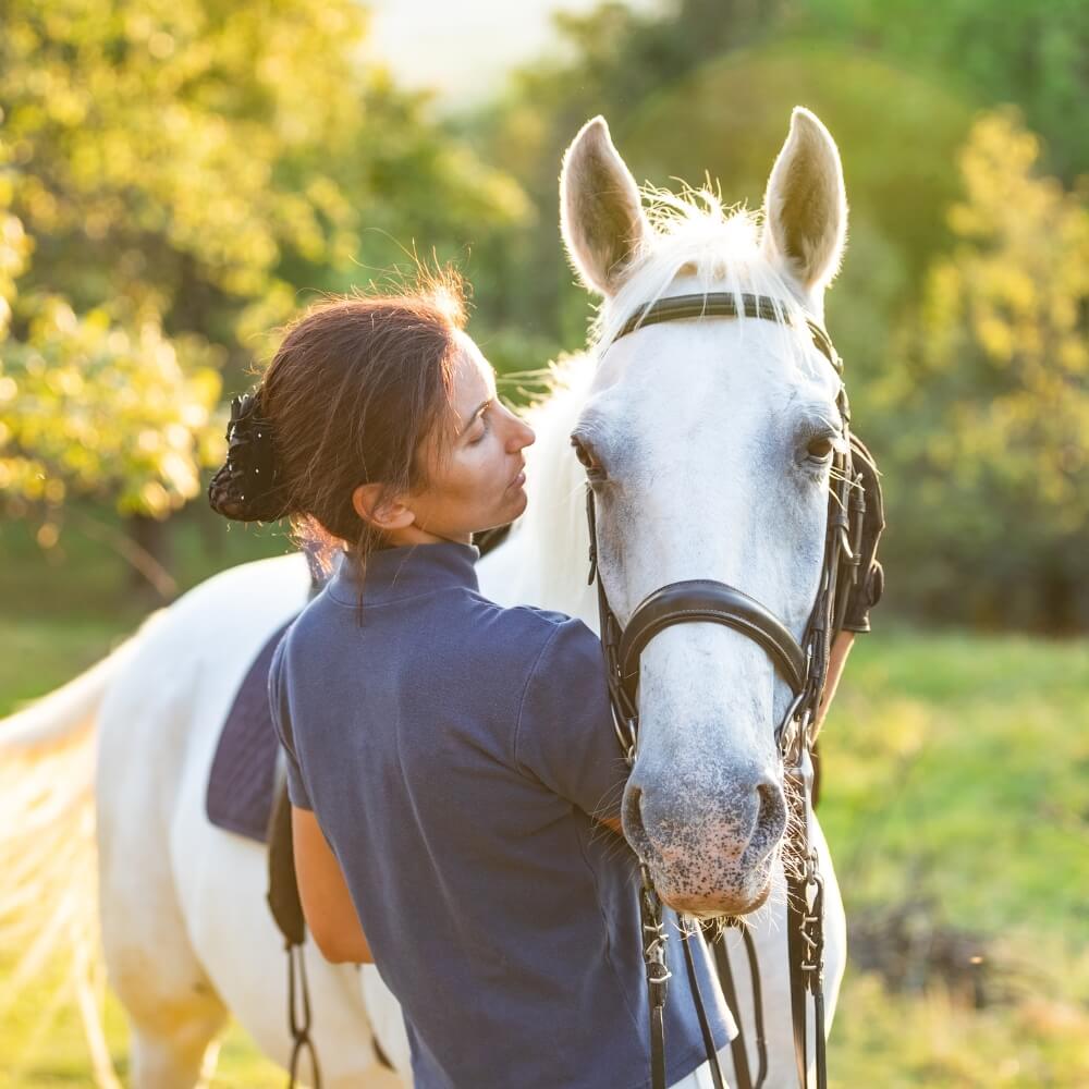 A vet in scrubs is petting a horse